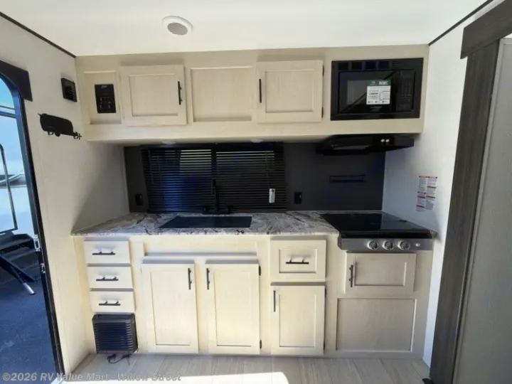 Modern RV rental kitchen with a stovetop, microwave, sink, and ample storage. Ideal for cooking on your next road trip.. Coachmen Shasta 2027