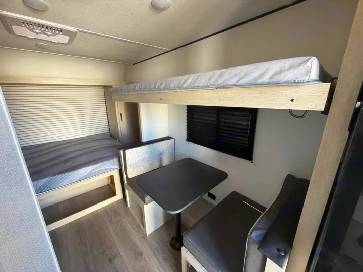 Cozy RV rental interior featuring bunk beds, a dinette, and a comfy bed, ideal for your next road trip adventure.. Coachmen Shasta 2027