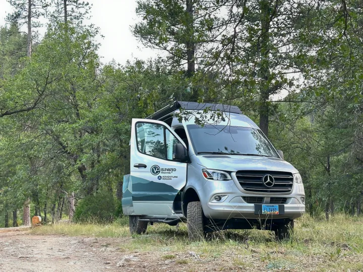 Silver Mercedes Sprinter rv rental by Elevated Vanworks, parked on a forest dirt road with door open, ready for off-grid adventure.. Mercedes-Benz Sprinter 2023