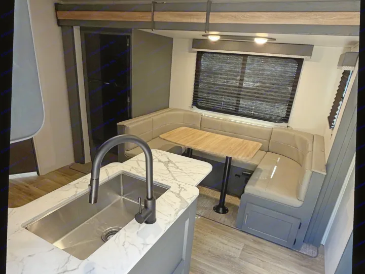 Modern RV rental interior: well-lit kitchen island with sink & faucet, and a comfy dinette with U-shaped seating & table.. Keystone RV Bullet Crossfire 2024