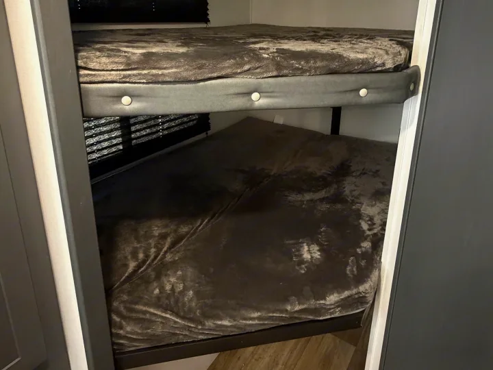 Compact dark grey bunk beds within an RV rental, designed for efficient and comfortable sleeping.. Keystone RV Bullet Crossfire 2024