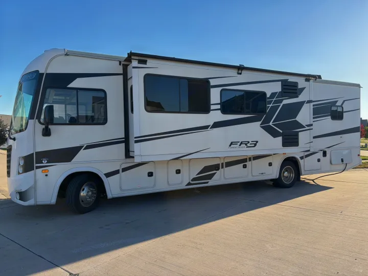 This white Forest River FR3 Class A motorhome RV rental, with black graphics, is parked on concrete, ready for your next adventure.. FR3 FR3 Motorhome 2022