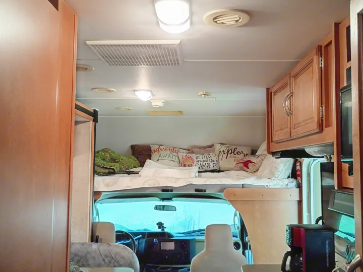 Cozy RV rental interior features cab-over bunk, dashboard, and wood cabinets.. Winnebago Minnie Winnie 2016