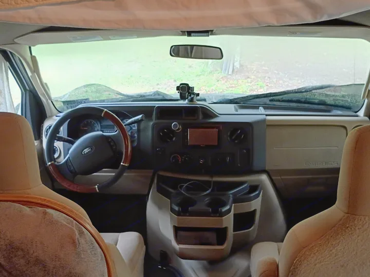 Inside a Ford E-Series rv rental: the cockpit, dashboard, and front seats are visible, viewed from the rear living area.. Winnebago Minnie Winnie 2016