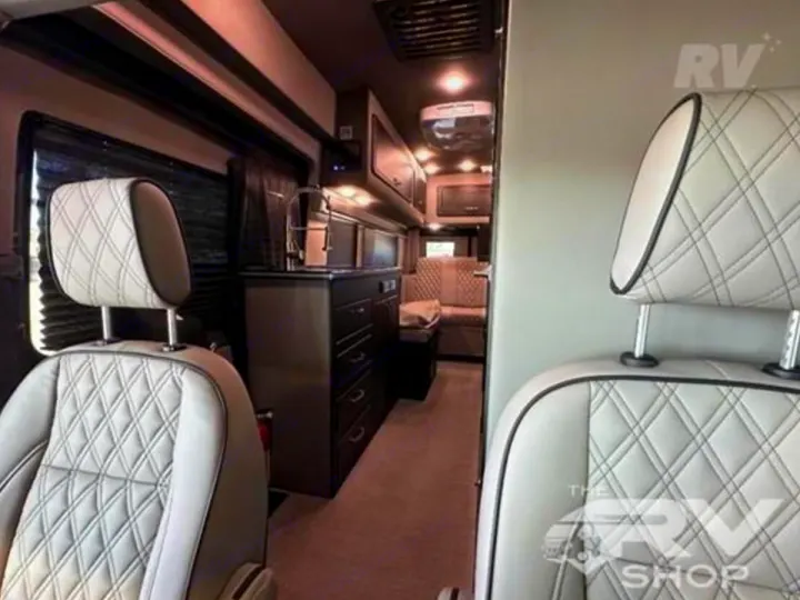 Luxury RV rental interior featuring quilted captain's chairs, a compact kitchen, and a rear lounge area.. Midwest Automotive Designs Passage 2024