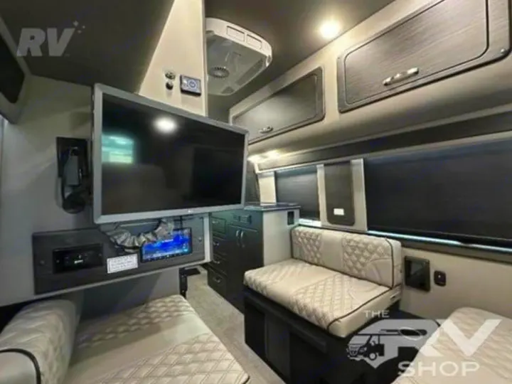 Modern RV rental interior: large TV, control panel, comfortable quilted sofas/beds, overhead cabinets, and blinds.. Midwest Automotive Designs Passage 2024