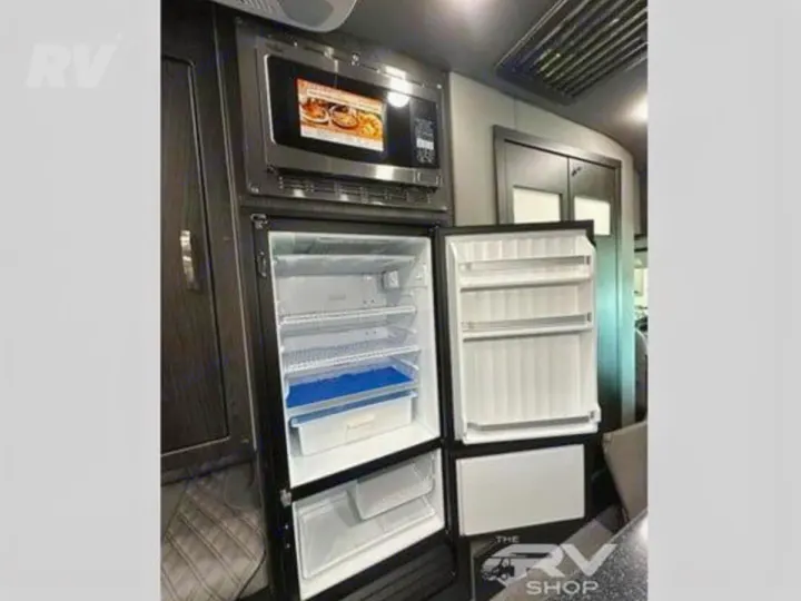 RV rental kitchen with open refrigerator, displaying multiple shelves, and a microwave oven for convenient storage.. Midwest Automotive Designs Passage 2024