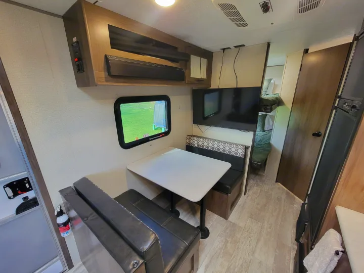 Cozy RV rental interior featuring a dinette, mounted TV, and bunk beds, ideal for family travel.. Forest River Avenger 2020