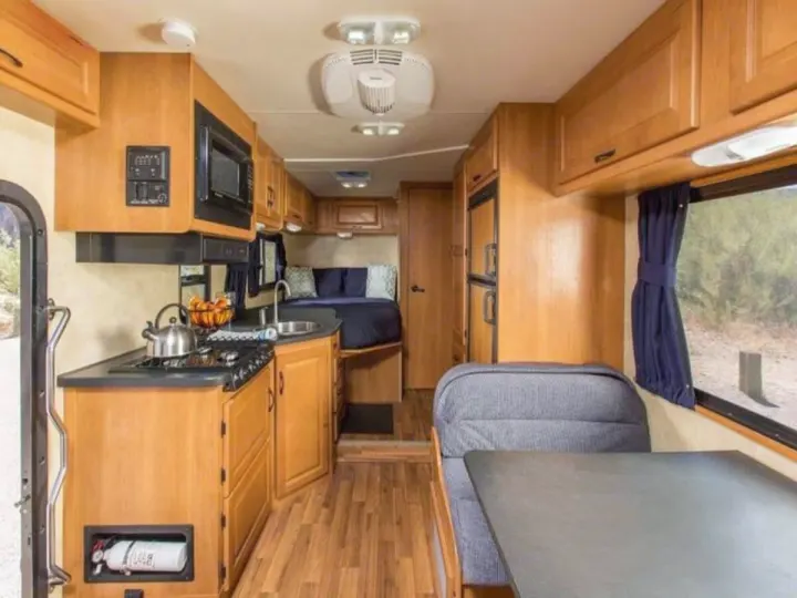 Spacious RV rental interior with a fully equipped kitchen, dinette, and cozy bed. Perfect for mobile living.. Thor Majestic 2023