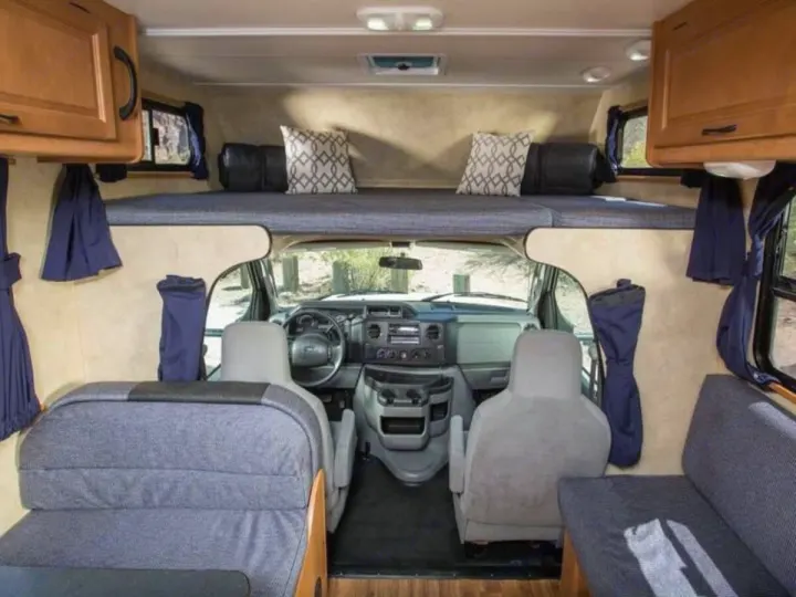 This rv rental shows the interior: an over-cab bunk bed, cockpit, and comfy seating. Ready for adventures!. Thor Majestic 2023