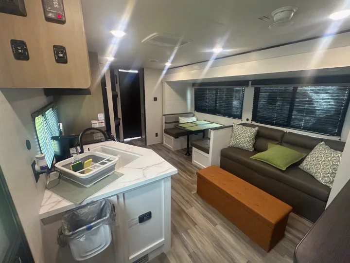 Modern RV rental interior featuring a bright kitchen, comfortable dinette, and cozy living area with a sofa.. Colt Open range 26dbs 2026