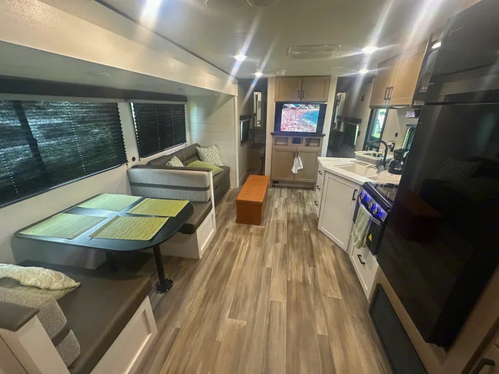 Inside a bright rv rental: a cozy living area, dining booth, kitchen, and TV. Ideal for family road trips & camping.. Colt Open range 26dbs 2026