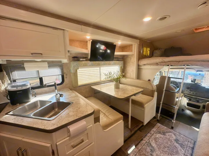Experience this clean rv rental interior featuring a functional kitchen, dining booth, and comfortable overhead bunk.. Winnebago Minnie Winnie 2018