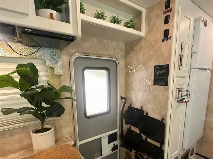 A cozy rv rental interior. Features include an entry door, plant, SONY player, control panel, hooks, and storage pockets.. Winnebago Minnie Winnie 2018