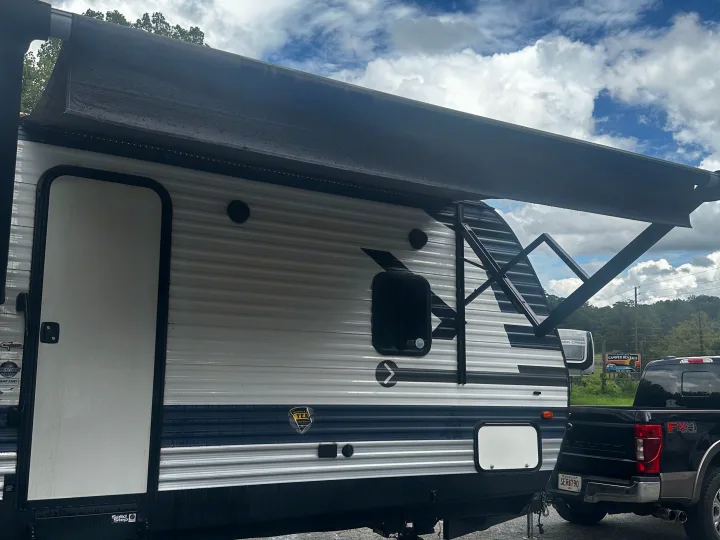 This white and blue RV rental, a travel trailer with an extended awning and Solid Step, is hitched to a black pickup.. Crossroads RV Zinger 2020