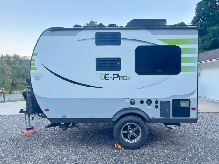 A sleek white and green Flagstaff E-Pro travel trailer sits on gravel, perfect for your next RV rental adventure.. Forest River Flagstaff E-Pro 2019