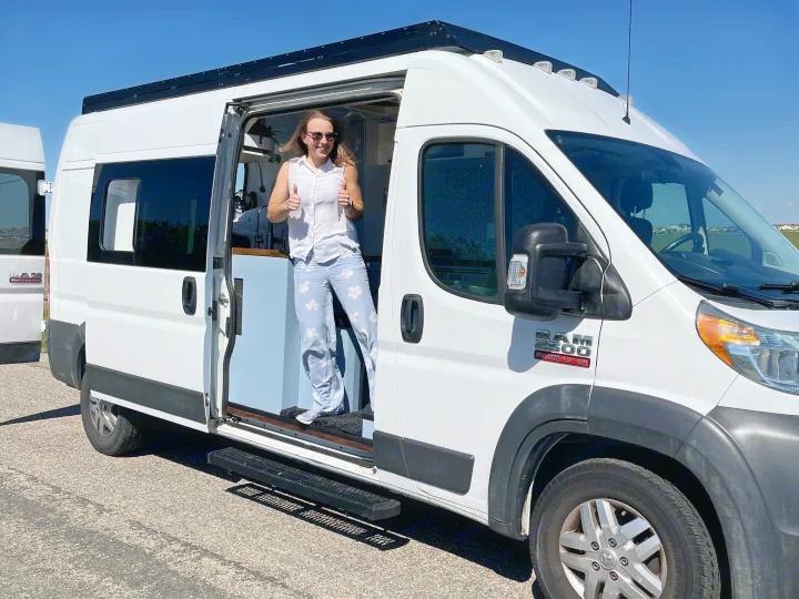 A happy woman gives thumbs-up from her customized white RAM ProMaster camper van, an ideal rv rental for adventure.. Dodge Ram Promaster 2500 2014