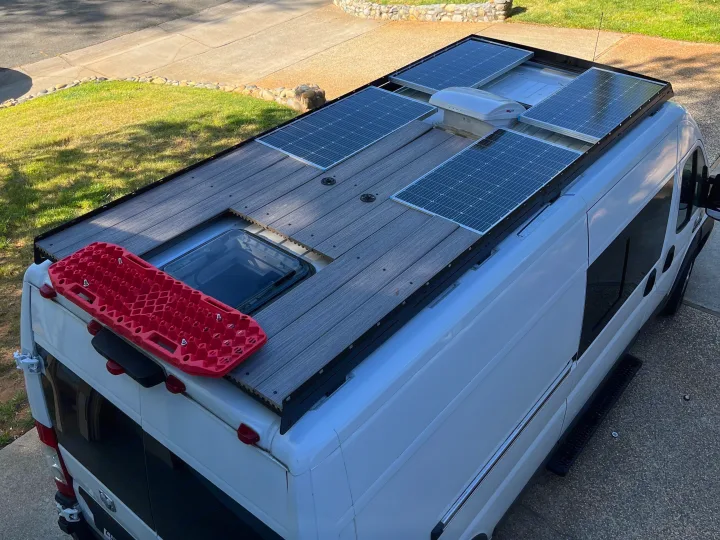Top-down view of an RV rental camper van featuring solar panels, a roof deck, and red recovery boards mounted on the rear.. Dodge Ram Promaster 2500 2014