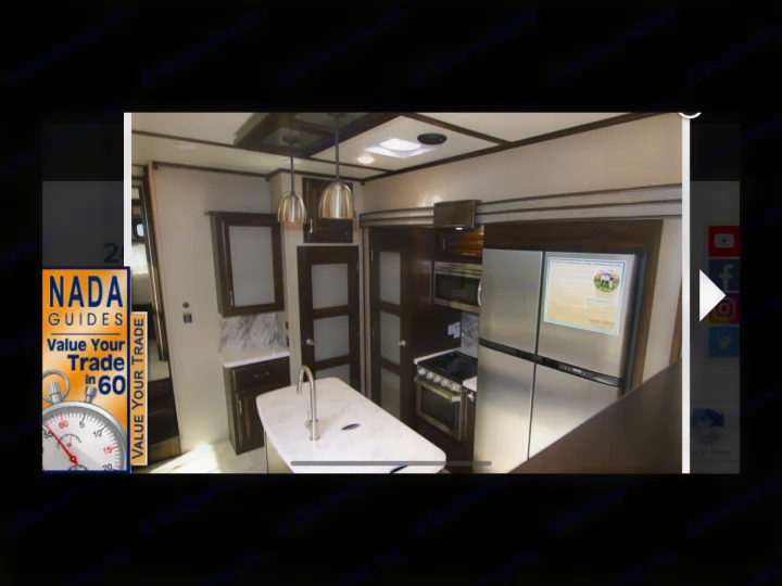 Interior of a modern RV rental kitchen featuring stainless steel appliances, an island, and dark wood cabinets.. Grand Design Momentum Toy Hauler 2020