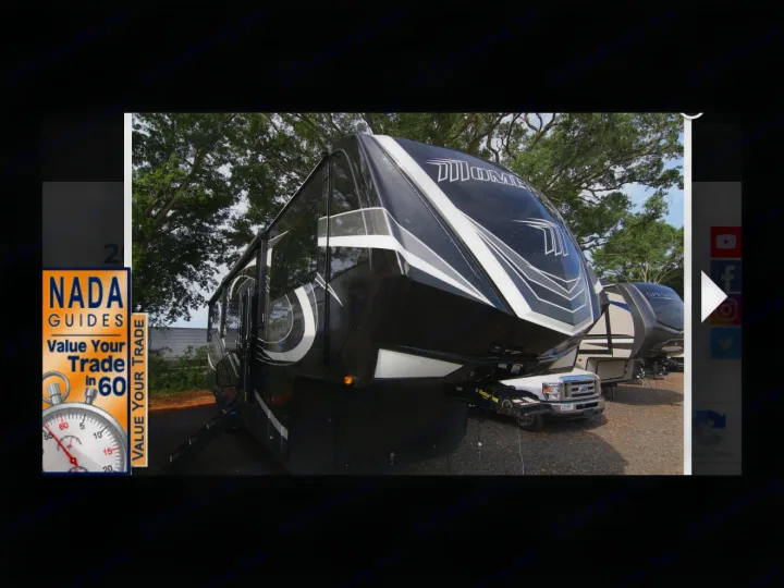 Black & white Momentum fifth-wheel RV, ideal for rental. NADA ad for trade-ins visible. Great recreational vehicle option!. Grand Design Momentum Toy Hauler 2020