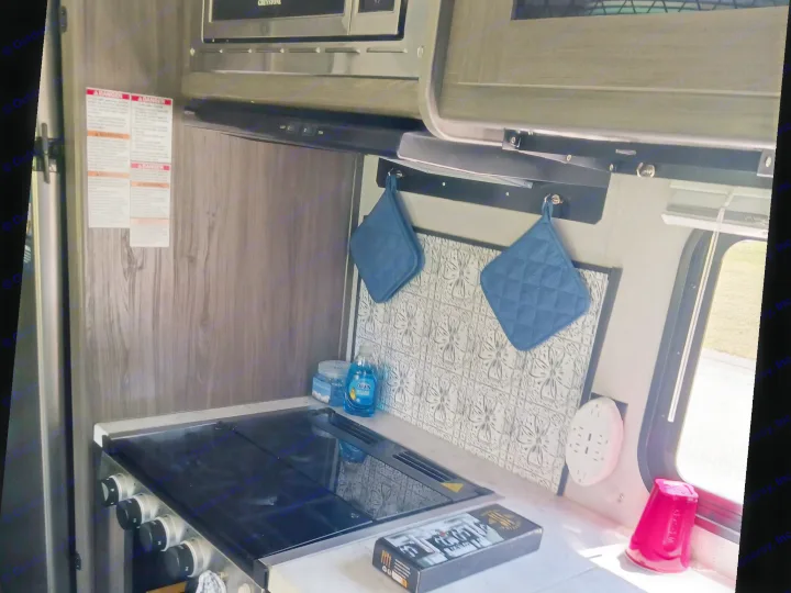 This RV rental kitchen features a stovetop, counter, Greystone microwave, backsplash, and kitchen essentials for your trip.. Forest River Shasta 2021