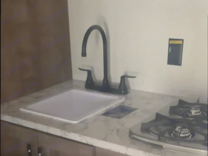 Compact RV rental kitchen features a modern black faucet, white sink, marbled countertop, and two-burner stove.. Keystone RV Springdale Mini 2025