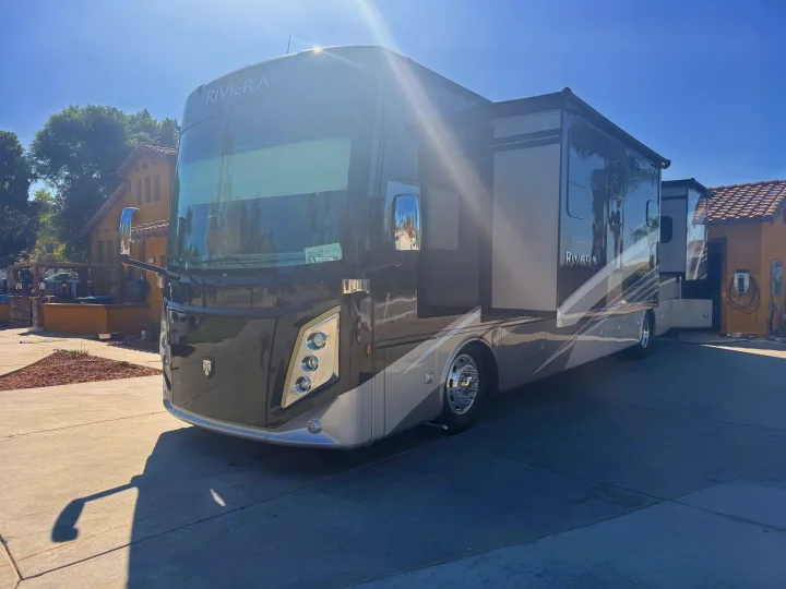 Large dark/silver Riviera motorhome RV rental, parked with slide-outs extended on a sunny day. Ready for adventure.. Thor Riviera 2024