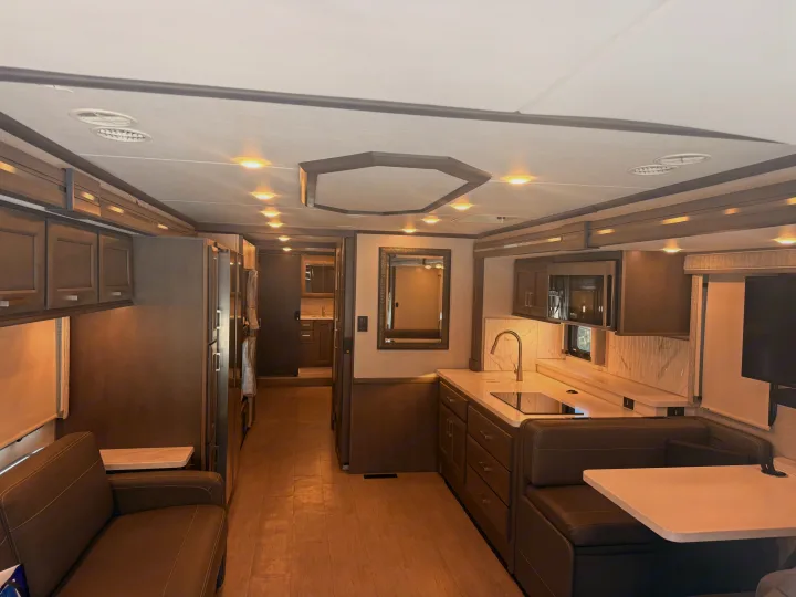 Spacious, modern rv rental interior showcasing kitchen, dining, and living areas with warm lighting.. Thor Riviera 2024