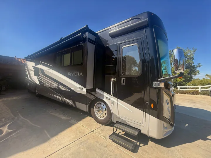 Black and grey Riviera Atlas rv rental parked on a sunny driveway. The spacious motorhome is ready for travel.. Thor Riviera 2024
