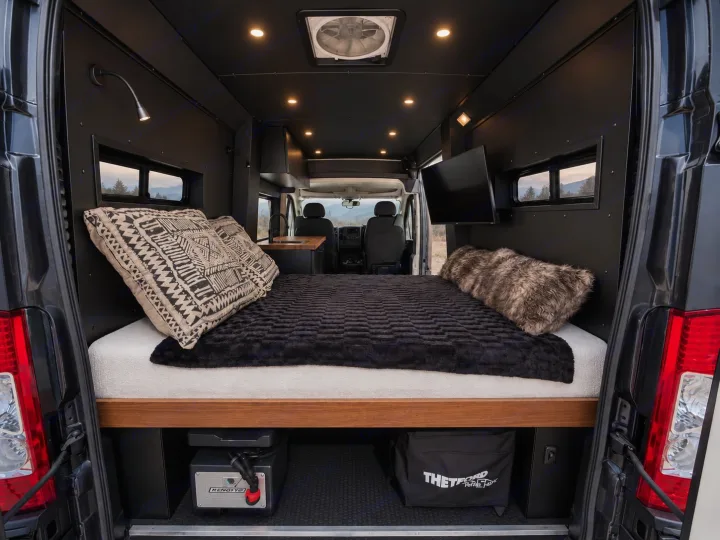 Sleek RV rental interior: large bed, integrated storage (power station, toilet), TV, and windows revealing outdoor scenery.. Dodge Ram 1500 2020