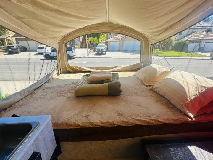 Relax in this RV rental pop-up camper's cozy bed with pillows and blankets. Enjoy street views through the mesh window.. Jayco 1209SC 2016