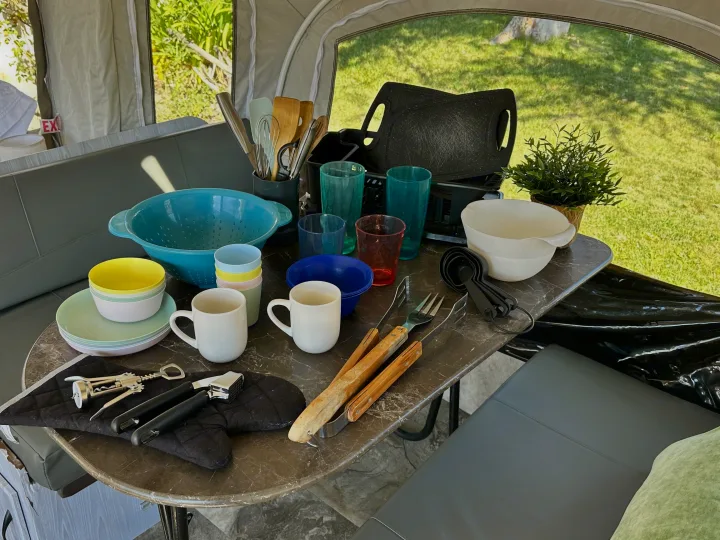 RV rental kitchen essentials: a colorful array of plates, bowls, cups, and cooking utensils ready for camping adventures.. Jayco 1209SC 2016