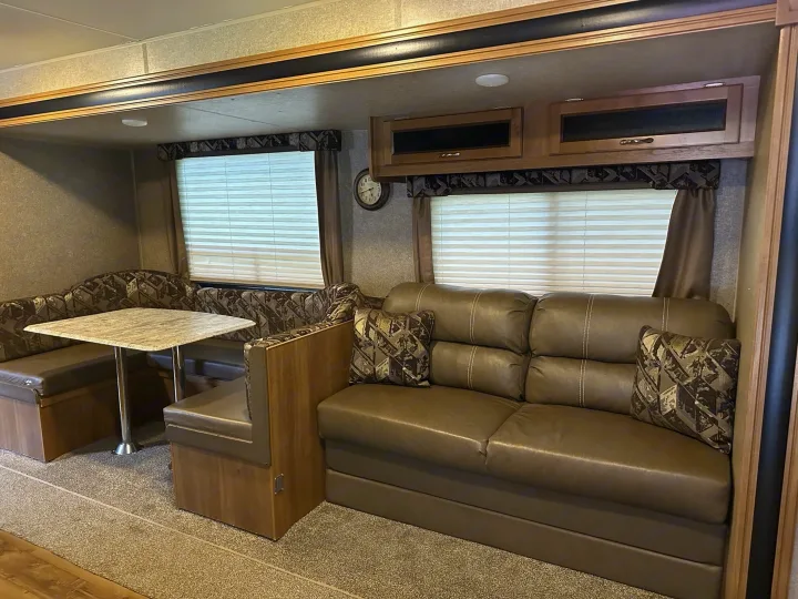 Comfortable RV rental interior with dinette seating, a plush sofa, and overhead storage.. Coachmen Catalina 2017