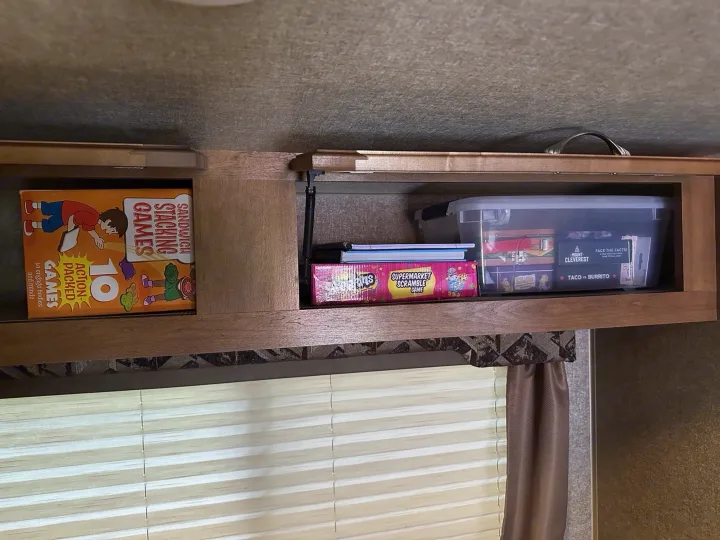 Overhead cabinet in an RV rental, packed with games: Sandwich Stacking, Supermarket Scramble, Taco vs Burrito. Ready for travel fun!. Coachmen Catalina 2017