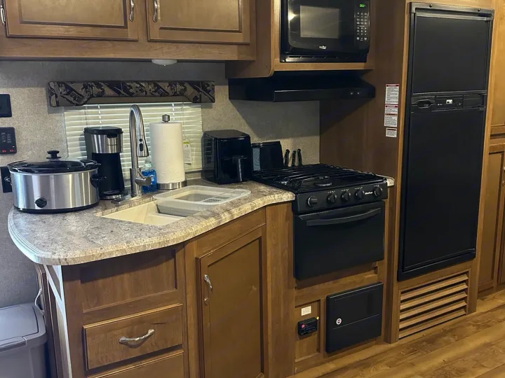 This fully equipped kitchen in an RV rental includes a sink, stove, microwave, fridge, slow cooker, coffee maker, and air fryer.. Coachmen Catalina 2017