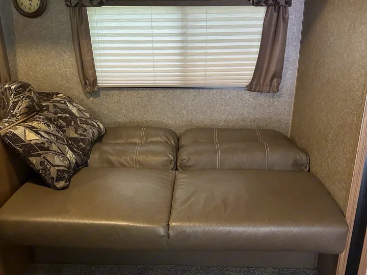 Cozy RV rental living space featuring a pull-out sofa bed, geometric accent pillow, and window treatments.. Coachmen Catalina 2017