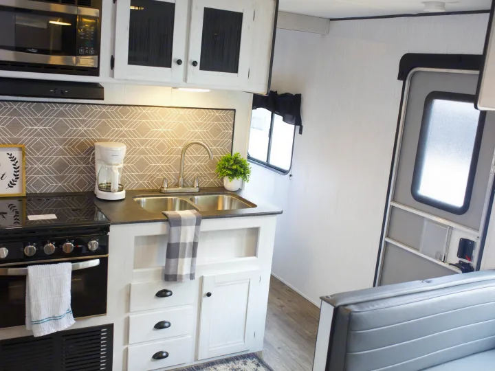 Modern RV rental kitchen: stove, microwave, sink, coffee maker, and a stylish geometric backsplash.. Heartland Trail Runner 2022