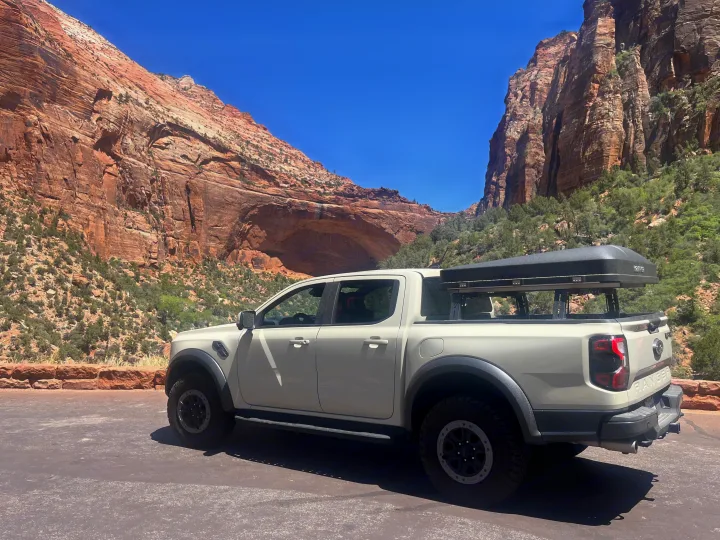 White truck with rooftop tent, perfect for an RV rental adventure, parked in a scenic red rock canyon.. Ford Ranger 2025
