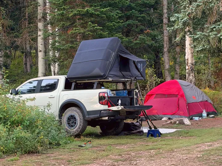 White truck with iKamper rooftop tent & ground tent, ready for a forest adventure. A unique 'rv rental' alternative for camping.. Ford Ranger 2025