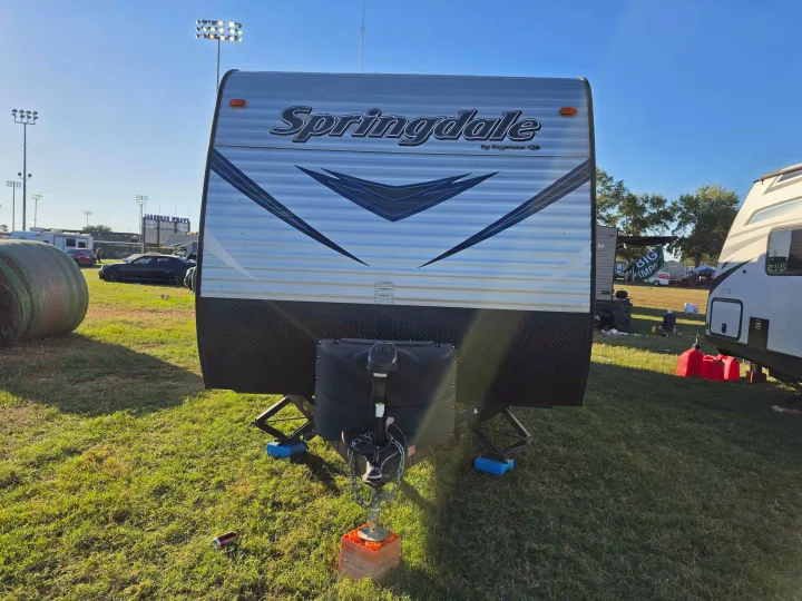 Front view of a Springdale RV rental by Keystone, parked on grass with stabilizing jacks at a campsite.. Keystone RV Springdale SSR 2018