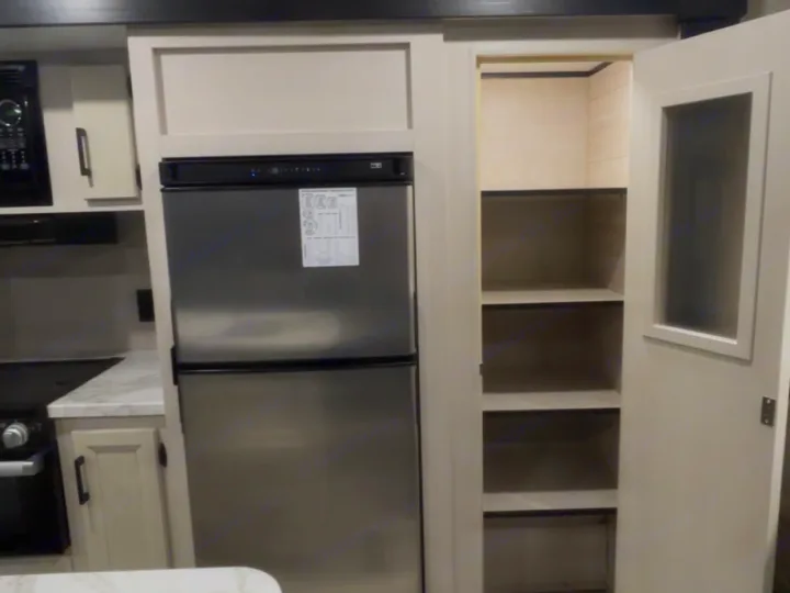 Explore this RV rental's modern kitchen! Features stainless steel appliances like a fridge, microwave, stove, and a spacious pantry.. Jayco Jay Flight 2023