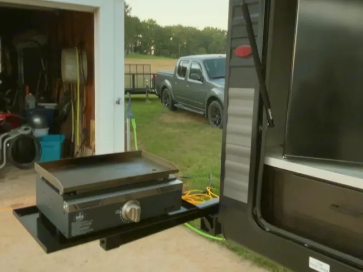 RV rental: Portable griddle ready for outdoor cooking on a travel trailer side mount. Truck & trailer visible in the field.. Jayco Jay Flight 2023