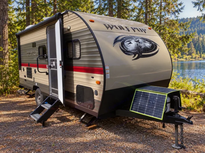 This Wolf Pup RV rental is set up lakeside with a portable solar panel, ready for outdoor camping adventures.. Forest River Cherokee Wolf Pup 2019