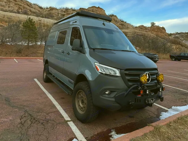 Adventure-ready Mercedes Sprinter van, ideal for an rv rental road trip, parked by rocky hills under a blue sky.. Winnebago Revel 2023