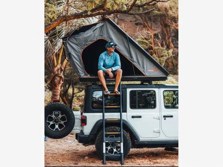 Man on Jeep with rooftop tent. A unique rv rental option for your next camping & outdoor adventure!. Jeep Wrangler 2025