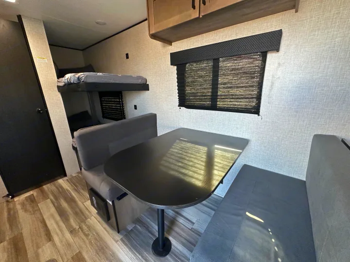Cozy RV rental interior with a dinette, bench seating, bunk beds, and wood-look floor, ideal for family travel.. Jayco Jay Flight 2025