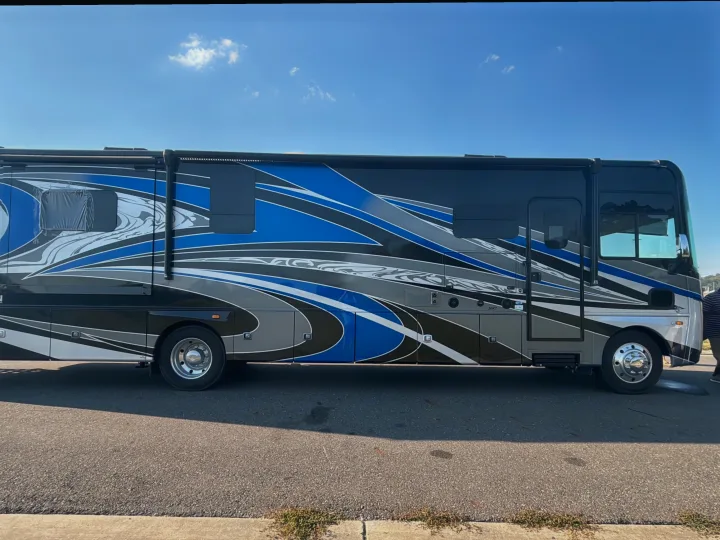 Sleek rv rental motorhome parked on asphalt under a blue sky, featuring a dynamic blue, black, white, and grey graphic design.. Georgetown GT7 2022
