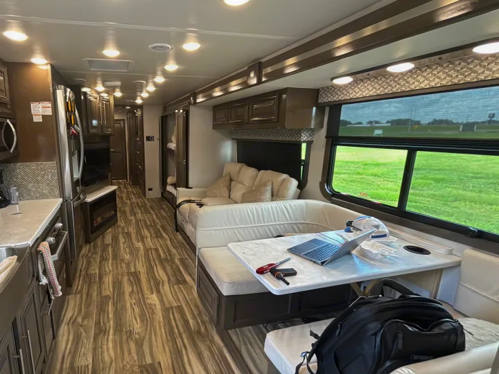 Inside a modern rv rental: full kitchen, dining area with laptop, and comfortable living space. Ready for your next adventure!. Georgetown GT7 2022