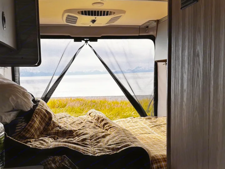 Cozy RV rental bed with an ocean view through the mesh screen. Perfect for a scenic campervan travel experience.. Winnebago Solis 59PX 2025