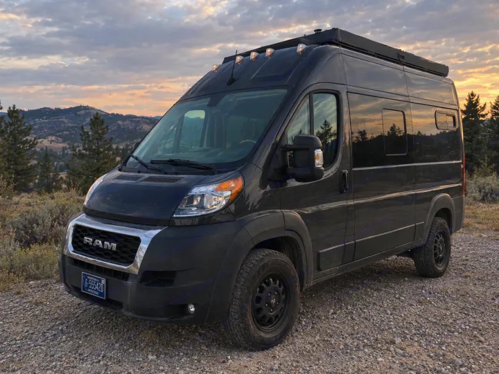 Explore Montana in this black Ram ProMaster camper van rv rental, parked on a scenic gravel road at sunset.. Dodge Ram 1500 2020